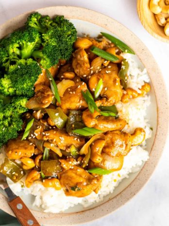 close up, overhead image of cashew chicken and rice on white plate