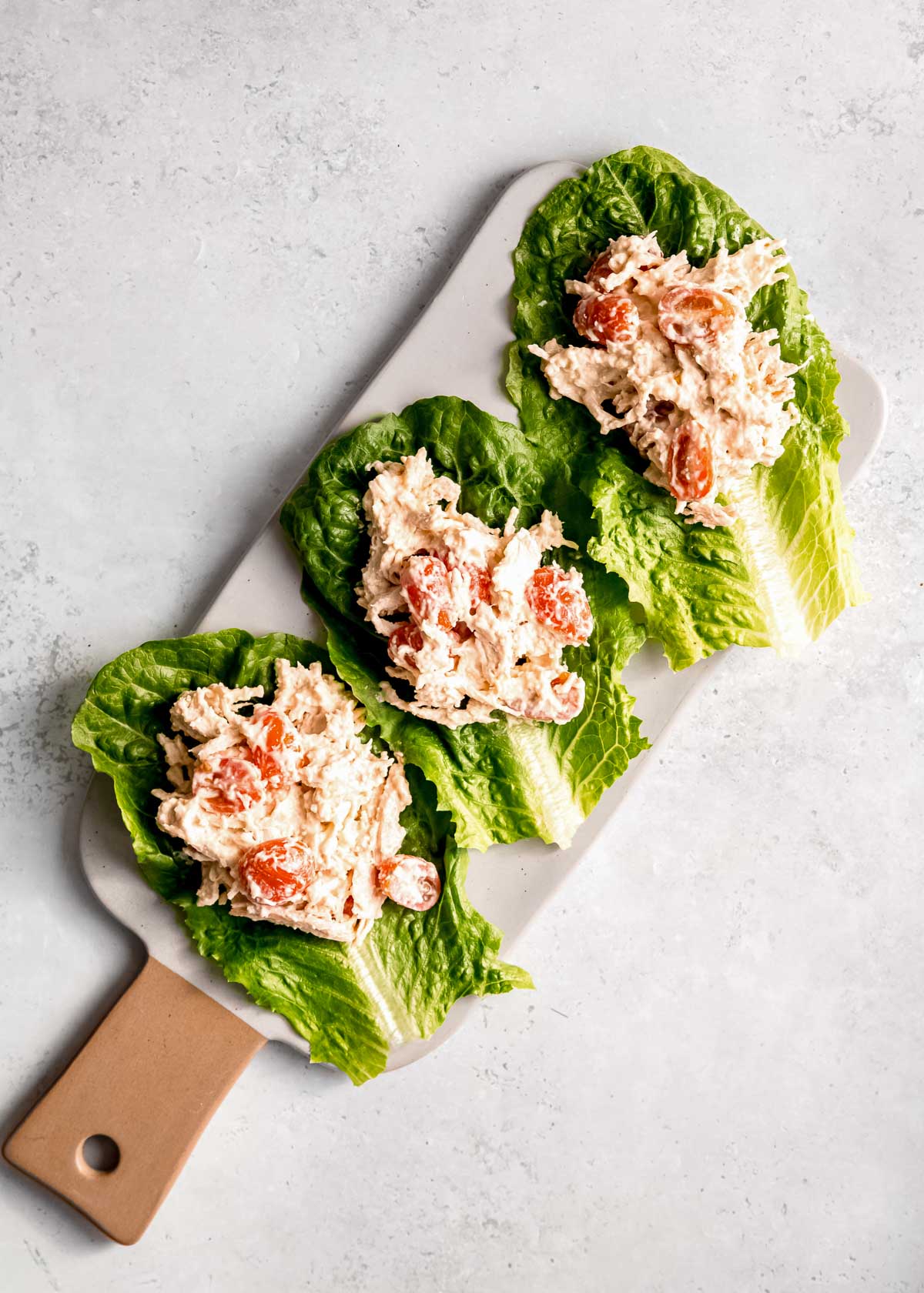 chicken filling on lettuce leaves on white cutting board