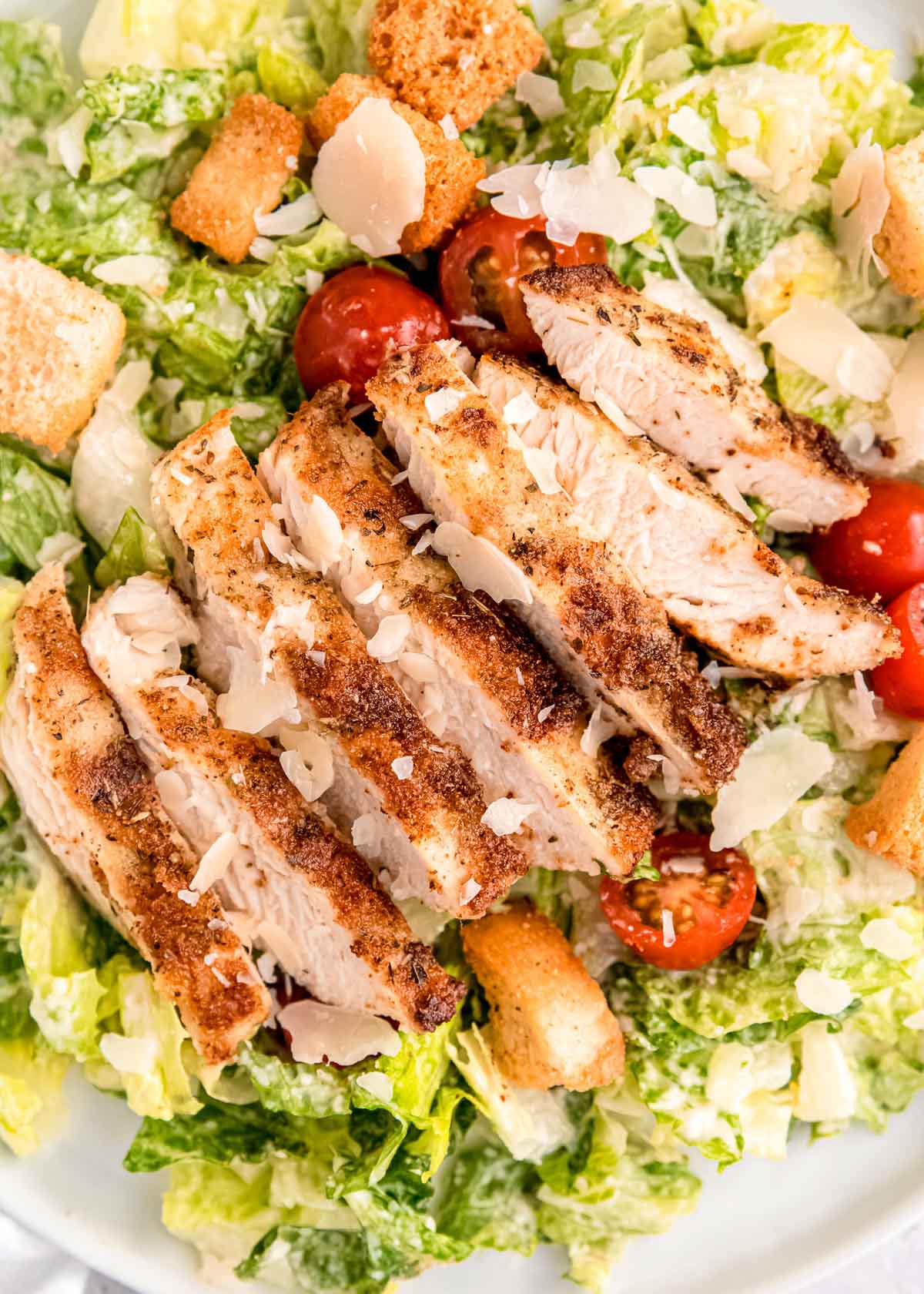 close up image of chicken caesar salad on white plate