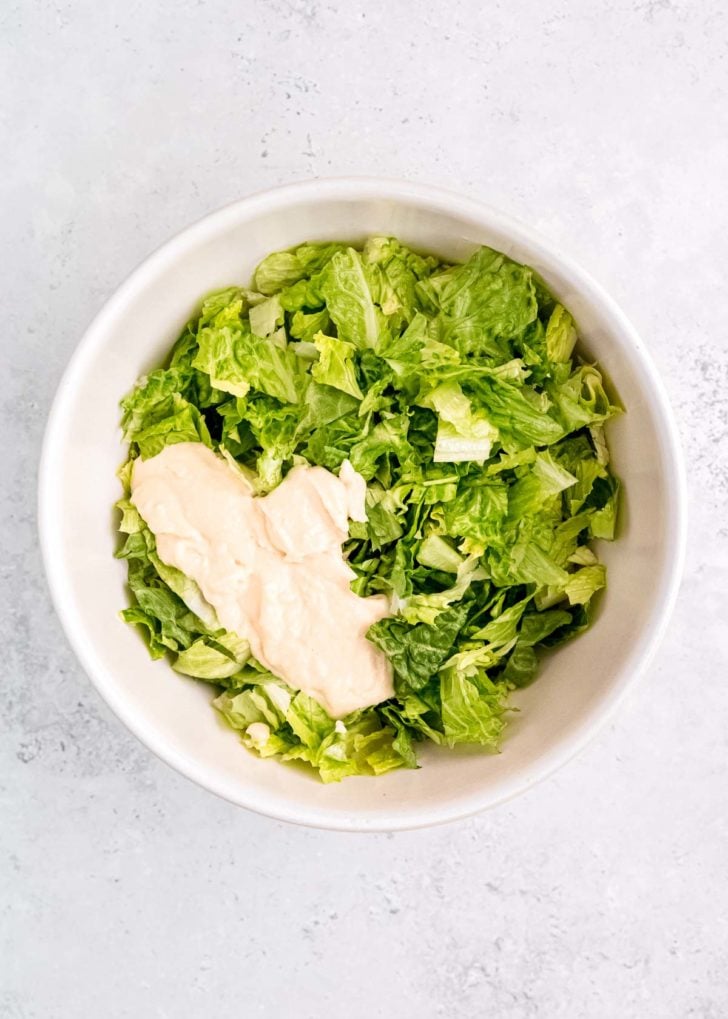 lettuce and caesar dressing in white bowl