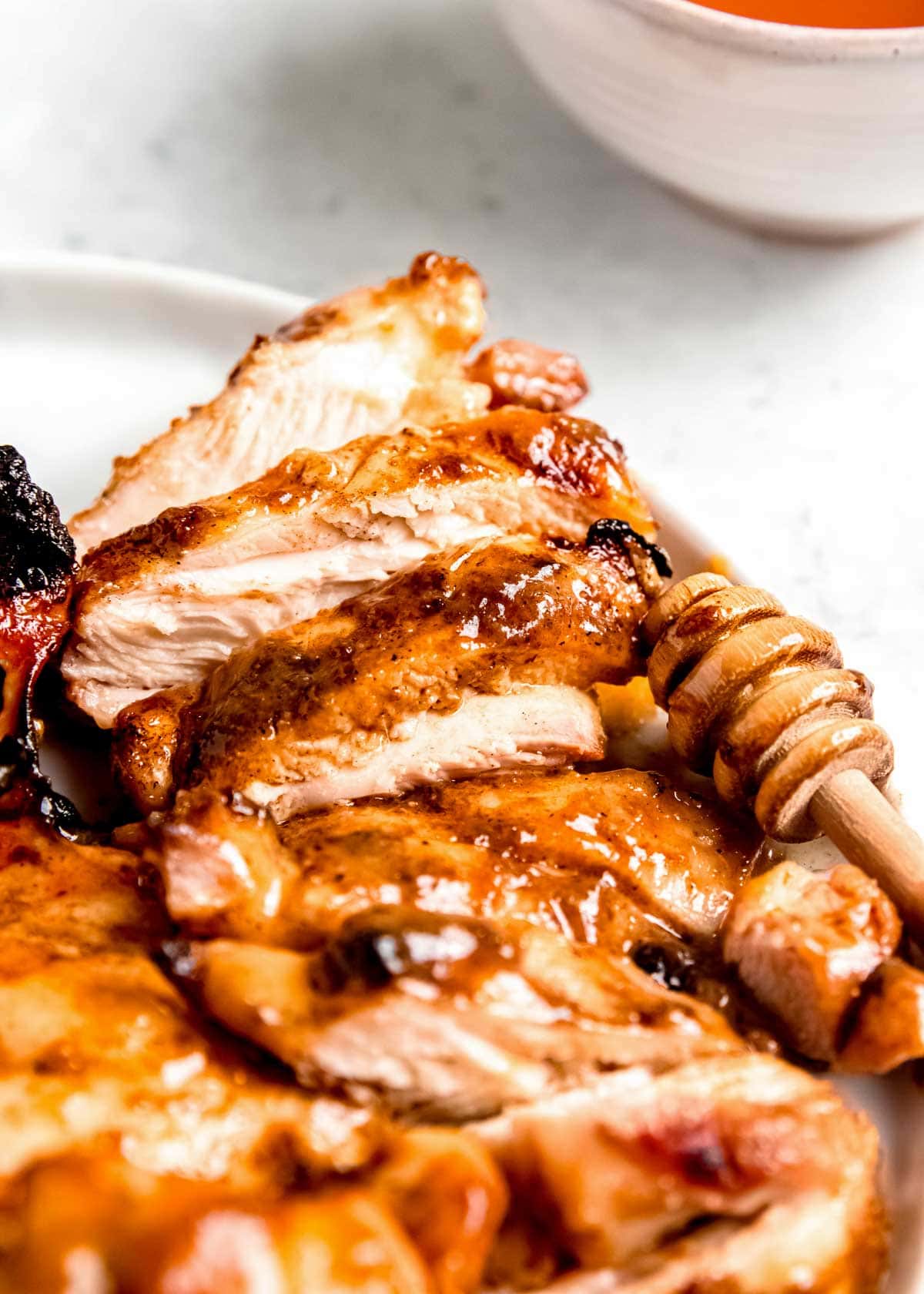 sliced honey mustard chicken on a white plate