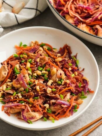 a white bowl of chicken egg roll in a bowl beside a large pot full of the keto dinner