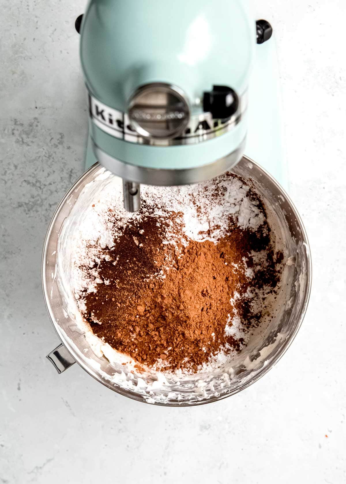cocoa powder, espresso powder, powdered sugar, and vanilla extract in an electric mixer bowl with whipped cream