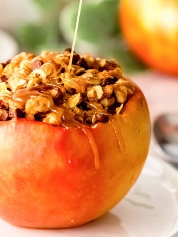 closeup of stuffed apples with chocolate oat filling, a drizzle of caramel sauce being added on top