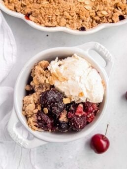 a bowl filled with the perfect cherry crisp and vanilla ice cream