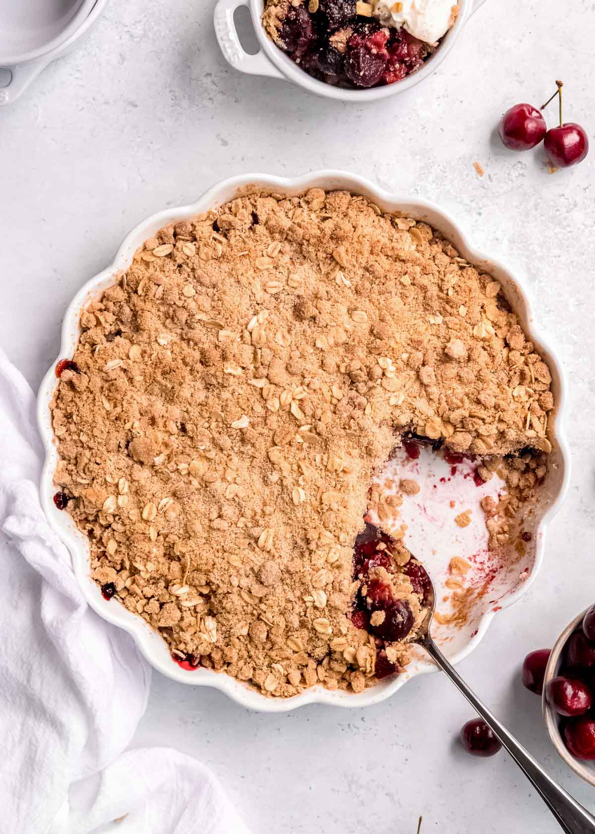overhead shot showing a classic cherry crisp baked in a white pan, missing one serving