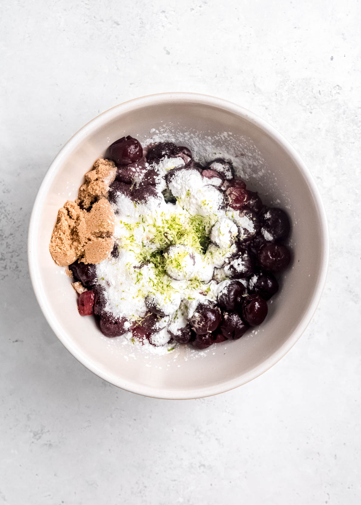 cherries, sugar, brown sugar, cornstarch, lime juice, and lime zest in a white bowl