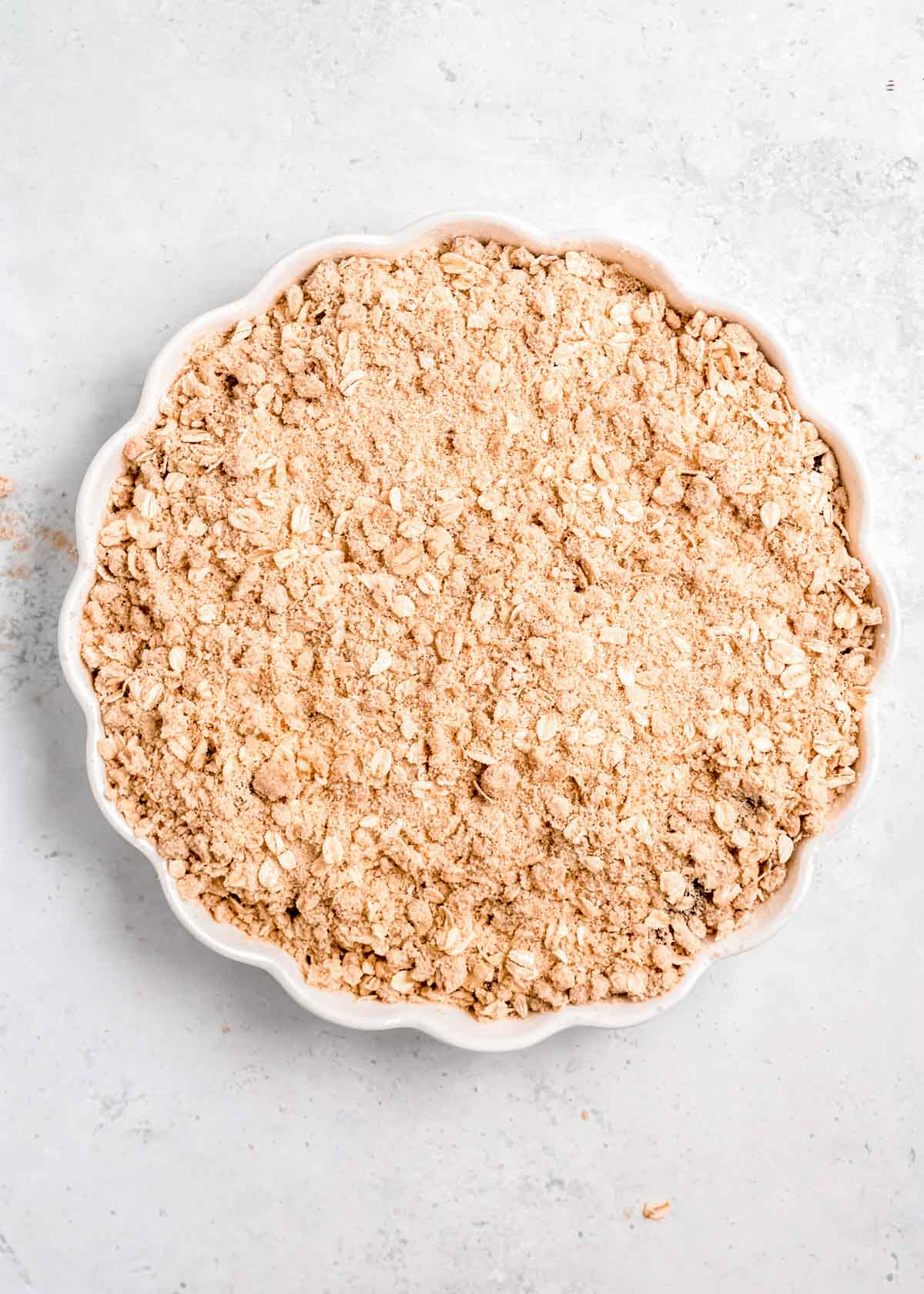 a crumbly oat topping added to a pie pan filled with a sweet cherry mixture