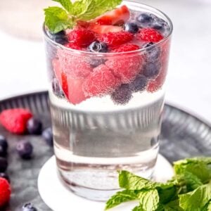 a full glass of white sangria topped with berries and mint
