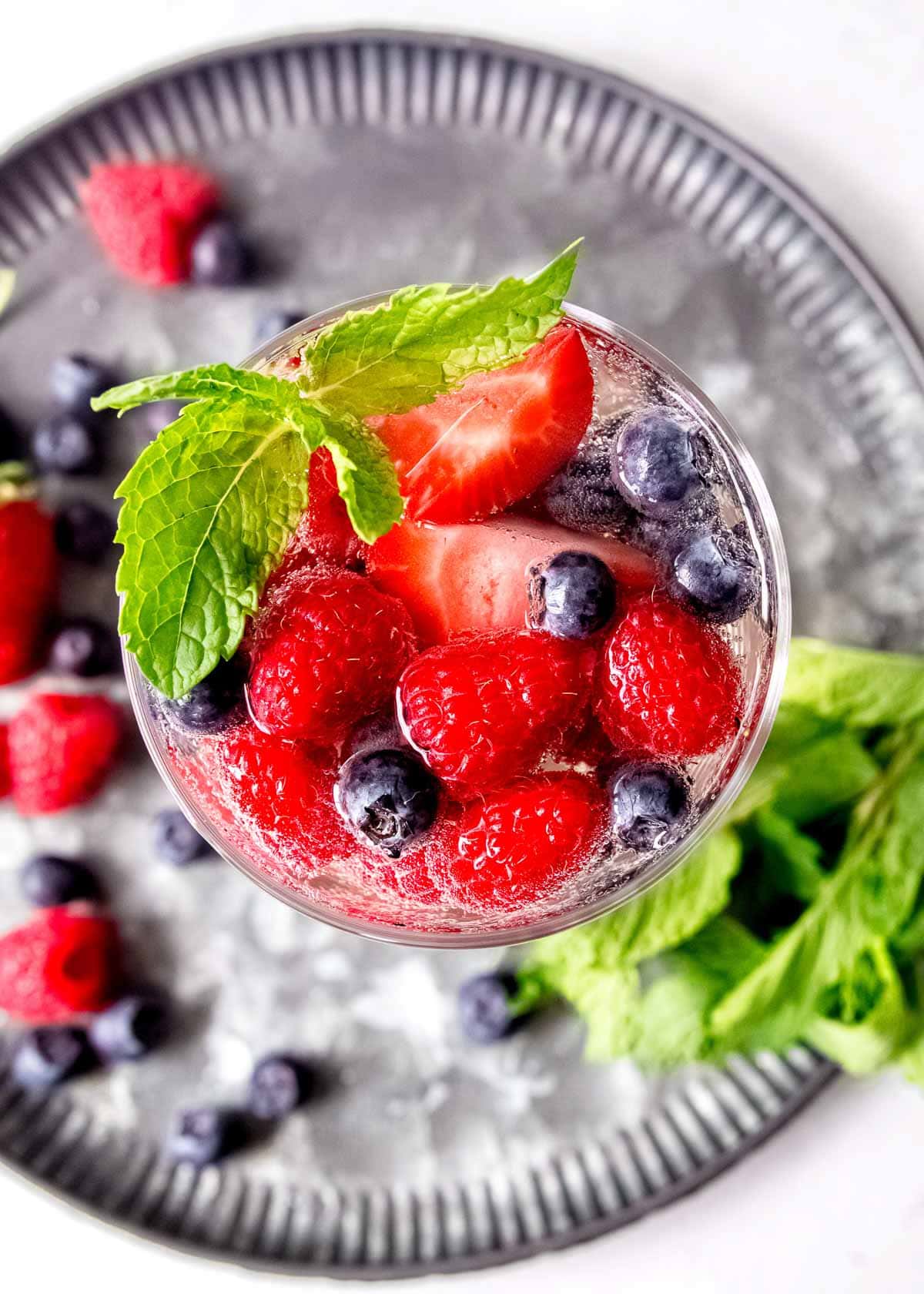 overhead shot showing a berry-filled white sangria garnished with a sprig of mint leaves