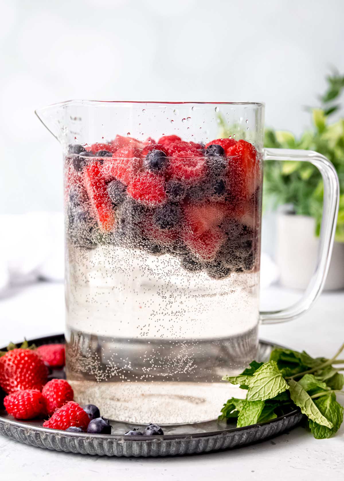 pitcher full of white sangria and red and blue berries