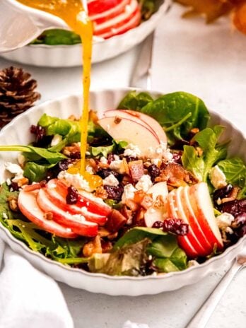 Maple-Dijon dressing drizzled over a fall apple salad with cranberries and bacon