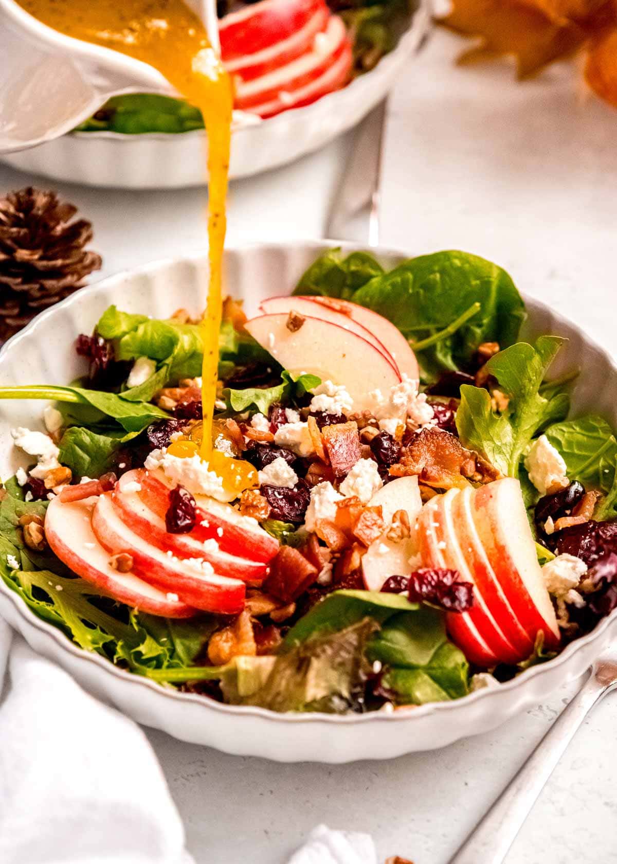 Maple-Dijon dressing drizzled over a fall apple salad with cranberries and bacon