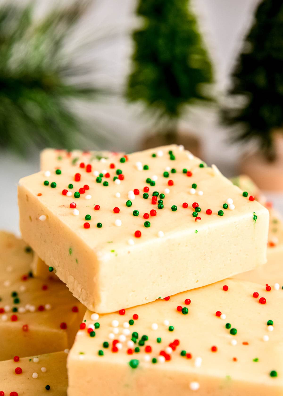 sugar cookie fudge stacked on a countertop in front of Christmas tree decorations