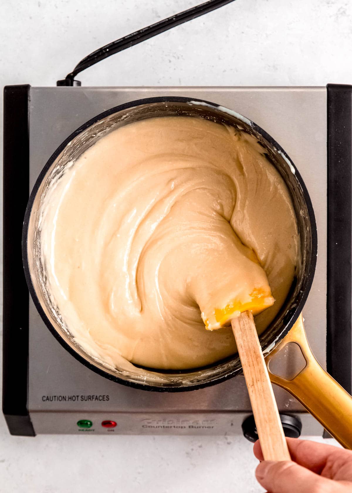 super creamy sugar cookie fudge being stirred in a saucepan