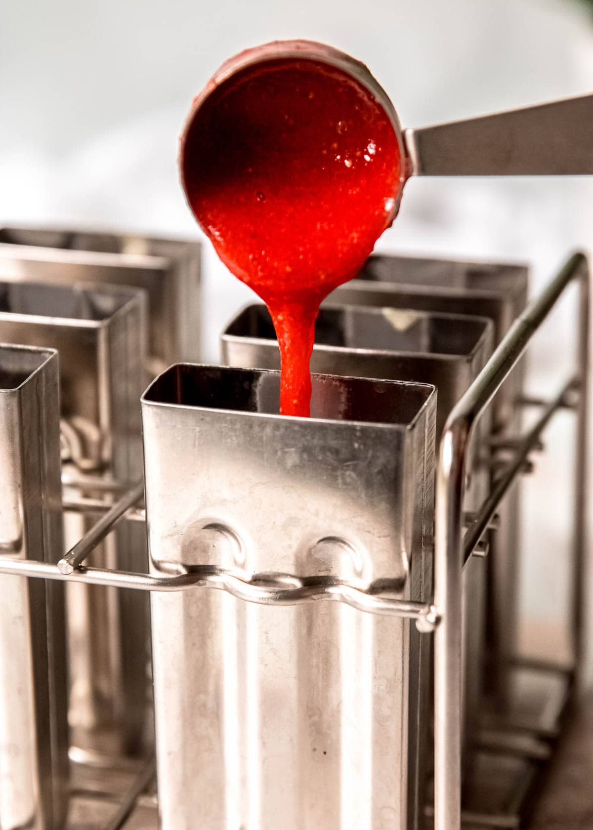 strawberry puree being poured into a popsicle mold