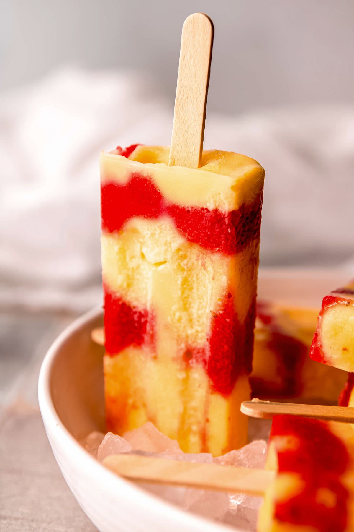 a strawberry popsicle standing up in a platter of ice and popsicles