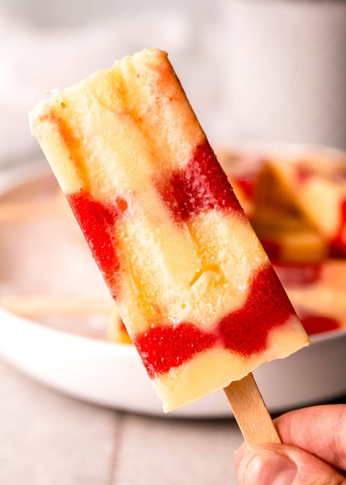 one strawberry pudding pop in front of a bowl of popsicles