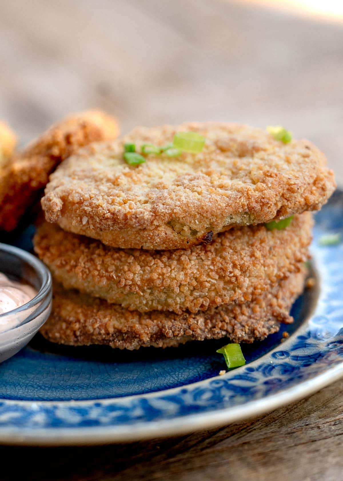 a stack of three crunchy fried green tomatoes on a plate with a side of sauce
