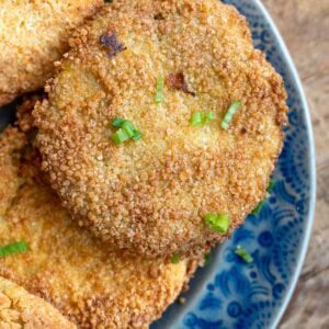 several fried green tomatoes on a blue platter, topped with chopped green onions