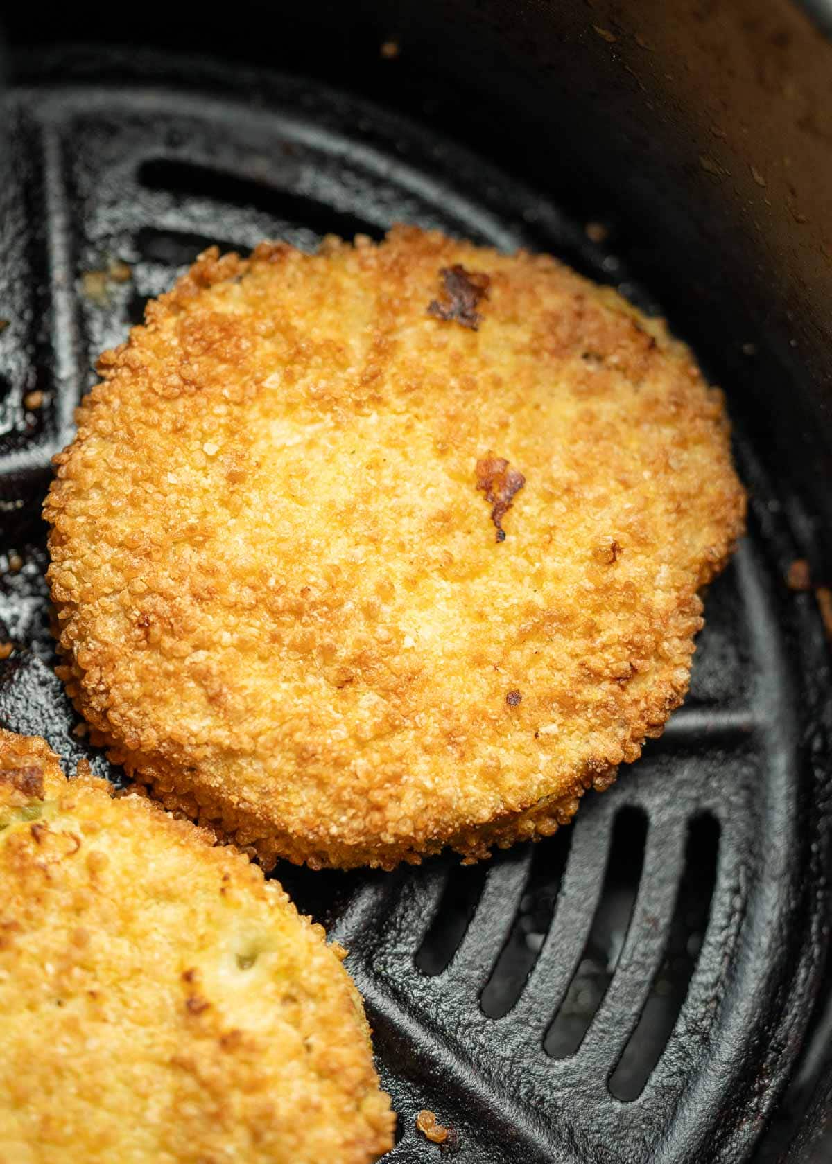 crispy fried green tomatoes in the basket of an air fryer