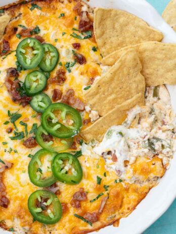 the best jalapeno popper dip topped with jalapenos, cheese, bacon, and chives and served with tortilla chips