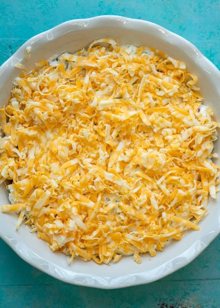 jalapeno popper dip in a pie plate topped with shredded colby jack cheese