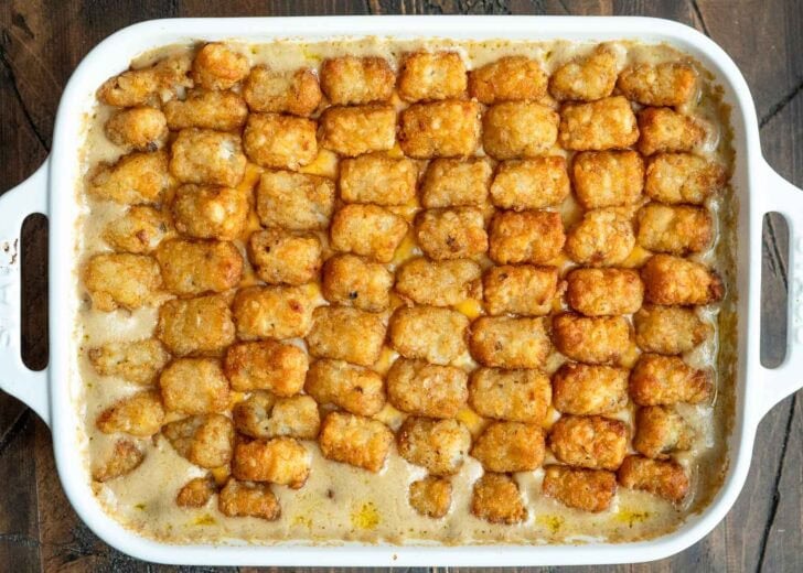 a baking dish filled with a creamy ground beef and veggie filling and topped with tater tots