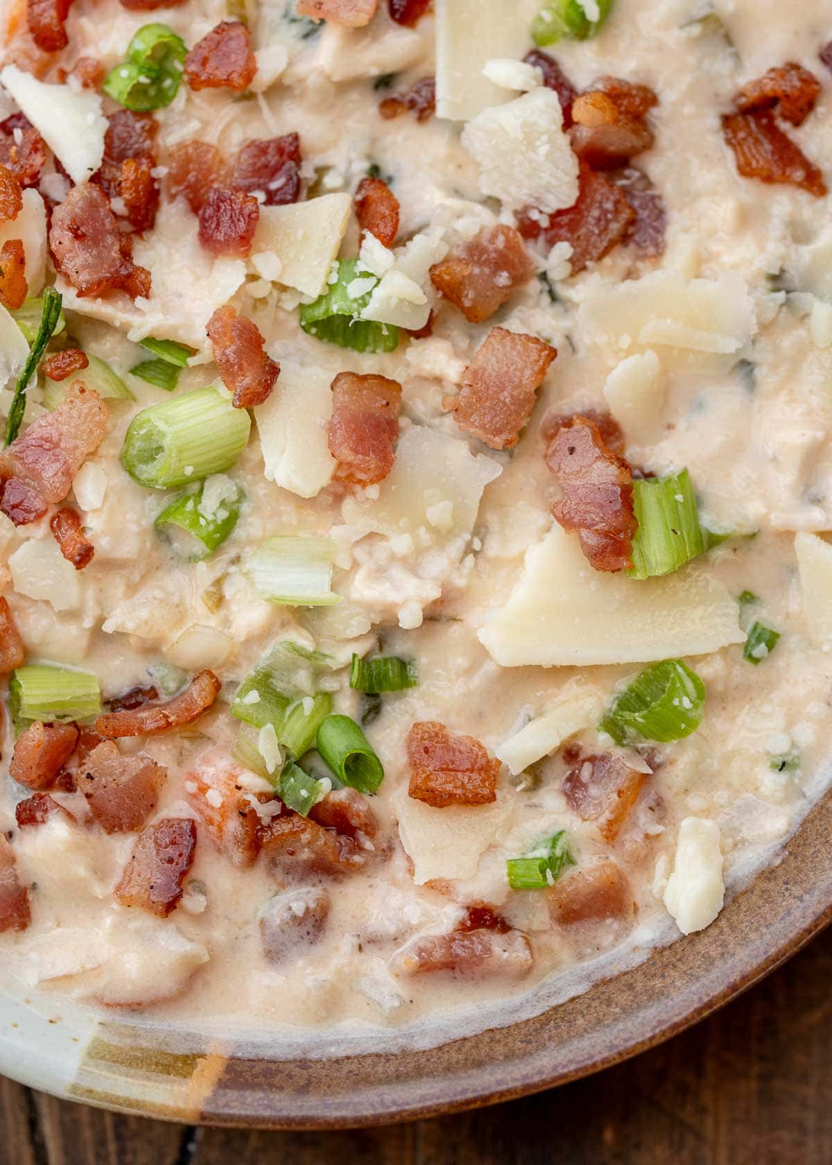 a bowl of creamy crack chicken soup garnished with chopped bacon, cheese, and green onions