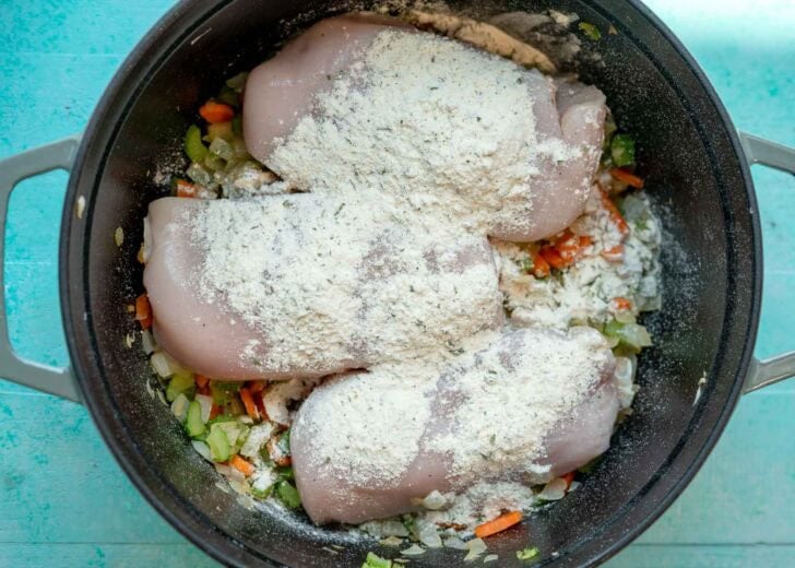 chicken breasts and ranch seasoning atop sauteed vegetables in a soup pot