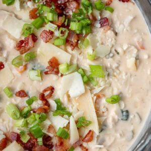a large pot full of crack chicken soup topped with cheese, green onions, and crispy bacon