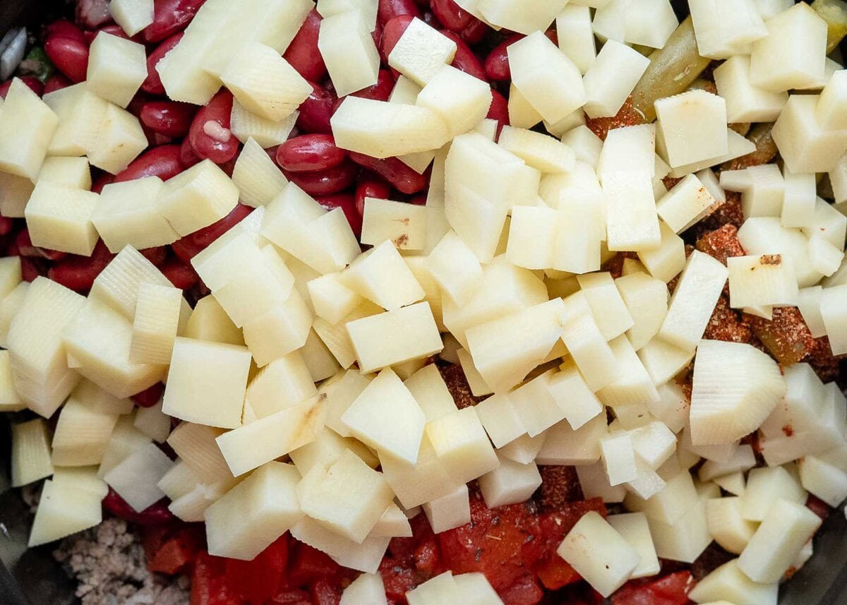 diced potatoes added into the crockpot for a cowboy beef and veggie soup