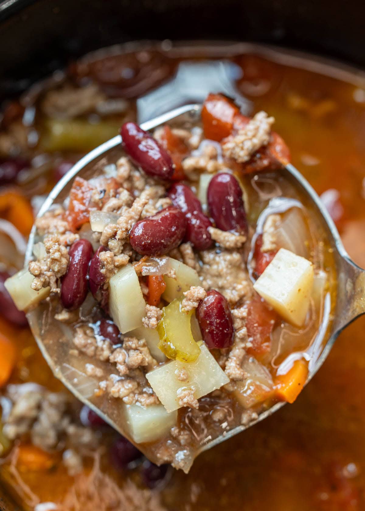 a ladle in a crockpot full of cowboy soup with ground beef