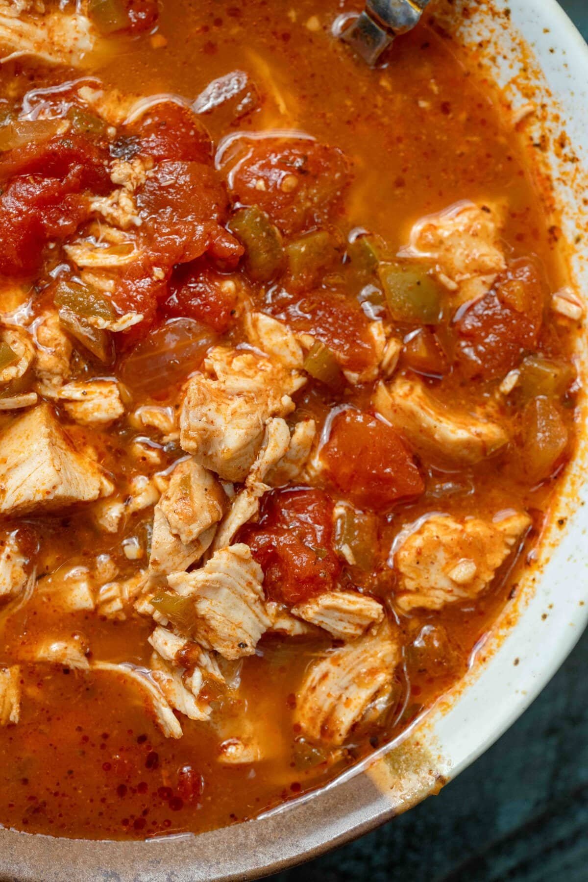 closeup of a spicy soup full of peppers and juicy shredded chicken