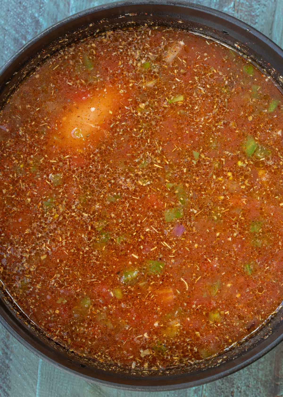 seasonings, canned tomatoes with green chilies, spicy tomato sauce, adobo sauce, and chicken broth in a heavy pot with chicken, peppers, and onions