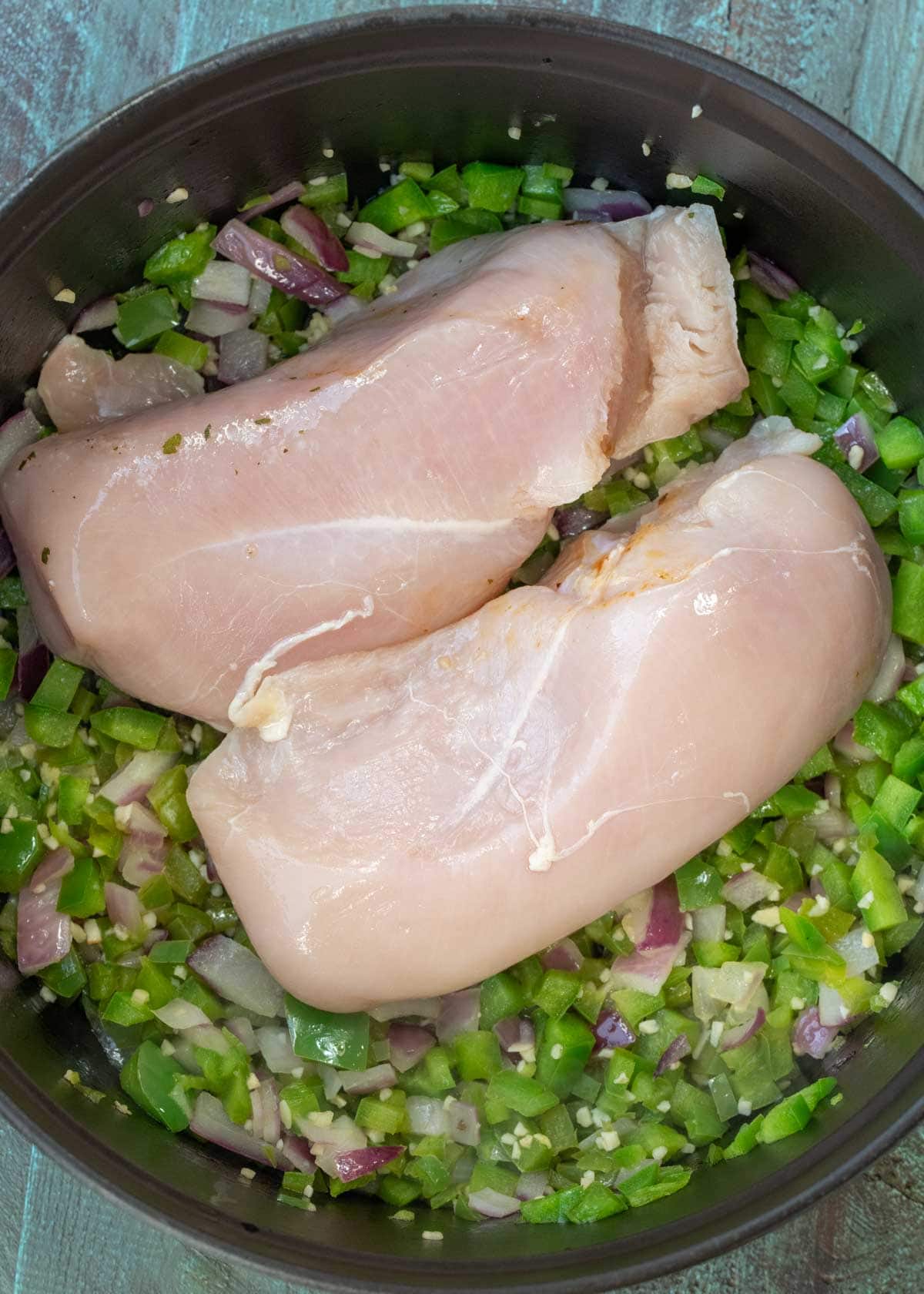 chicken breasts atop sauteed peppers and onion