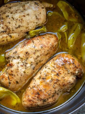 slow cooker full of chicken breasts in "mississippi sauce" with ranch and pepperoncinis