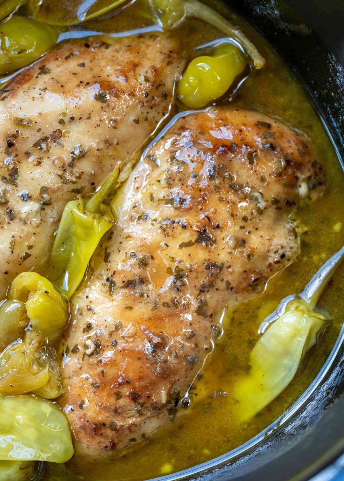 slow cooker full of chicken breasts in "mississippi sauce" with ranch and pepperoncinis
