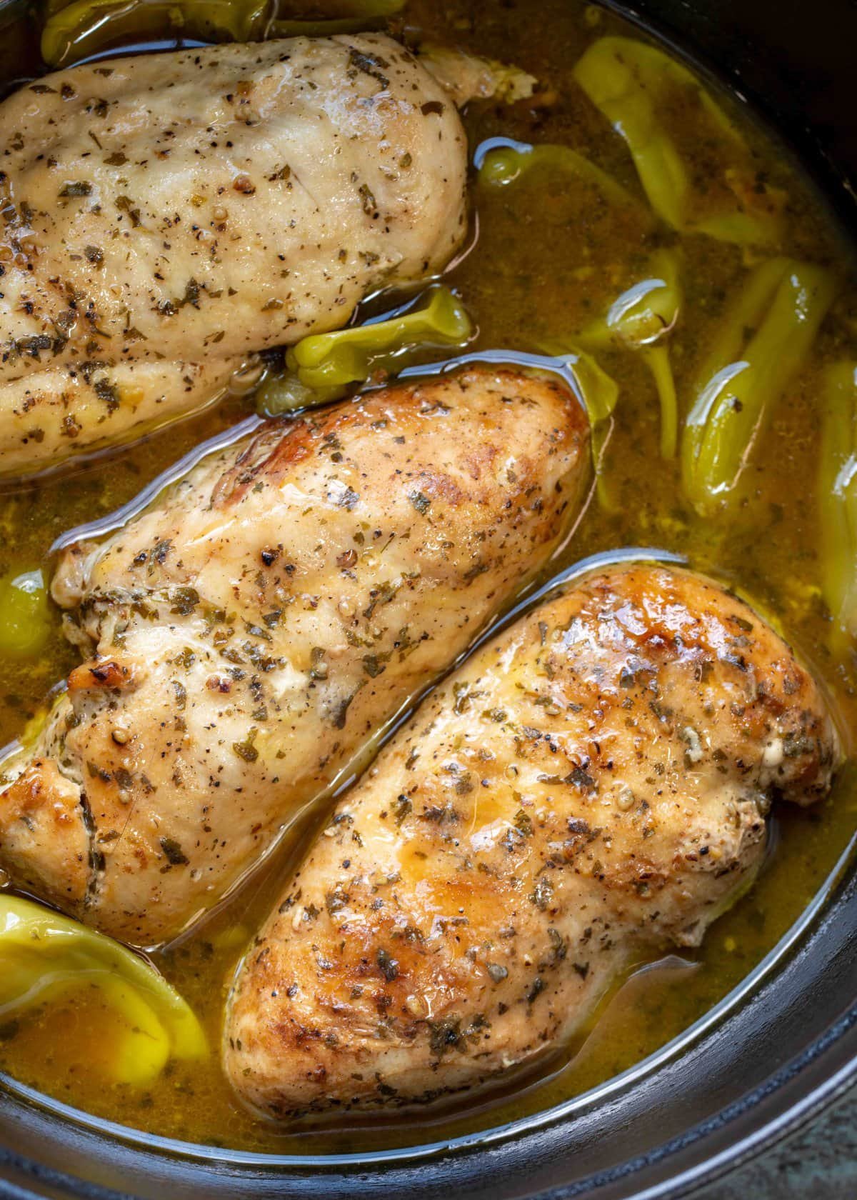 slow cooker full of chicken breasts in "mississippi sauce" with ranch and pepperoncinis