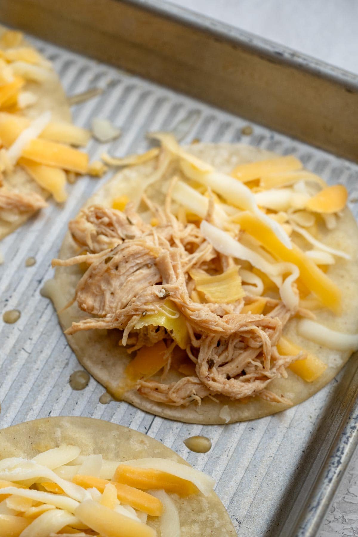 shredded cheddar cheese and mississippi chicken on a street taco sized tortilla