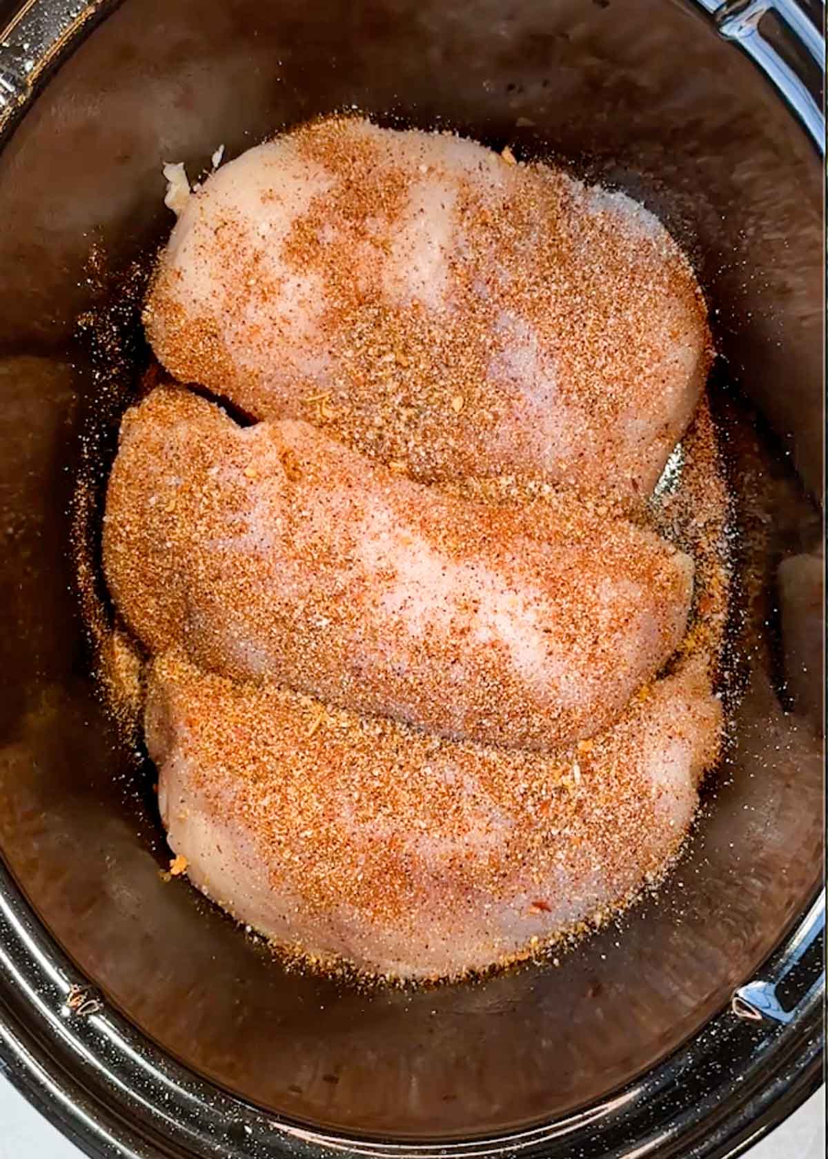 chicken breasts covered in taco seasoning in a slow cooker