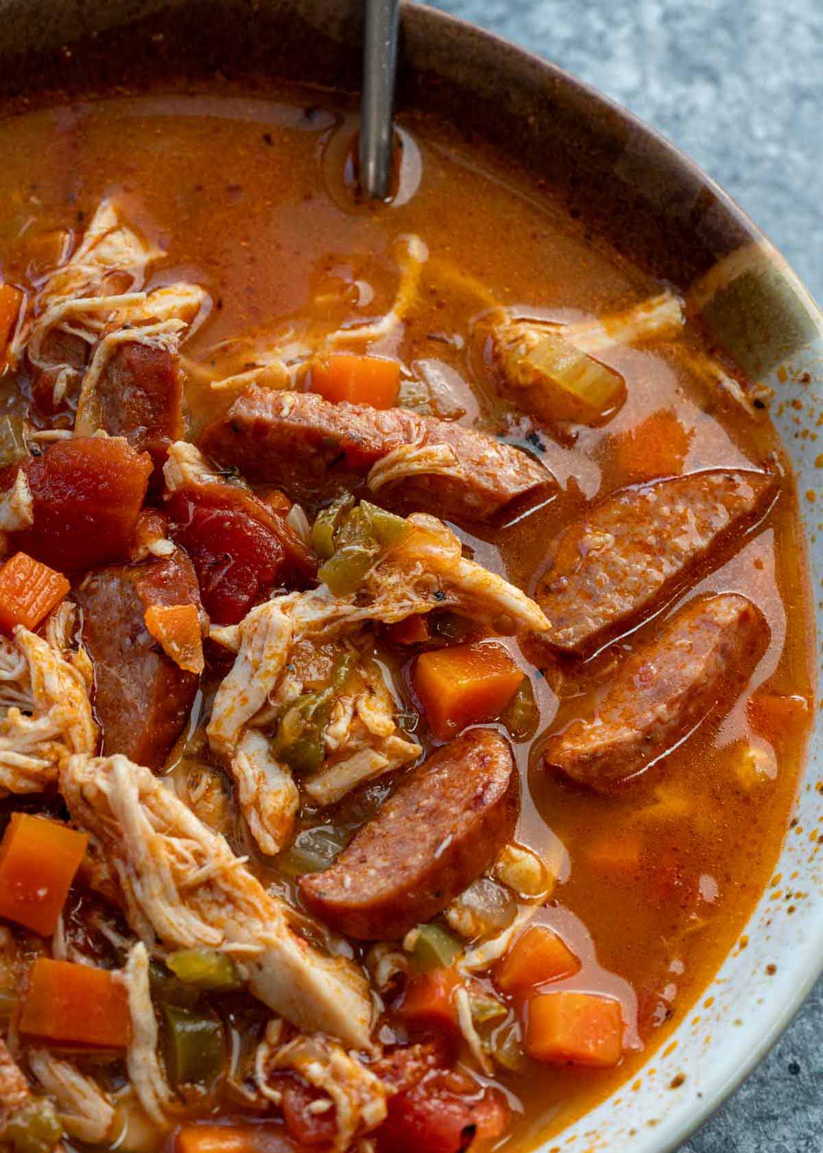a bowl of sausage soup with chicken and veggies