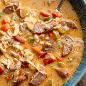 a bowl full of creamy cajun chicken and sausage soup with a spoon