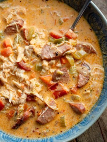 a bowl full of creamy cajun chicken and sausage soup with a spoon