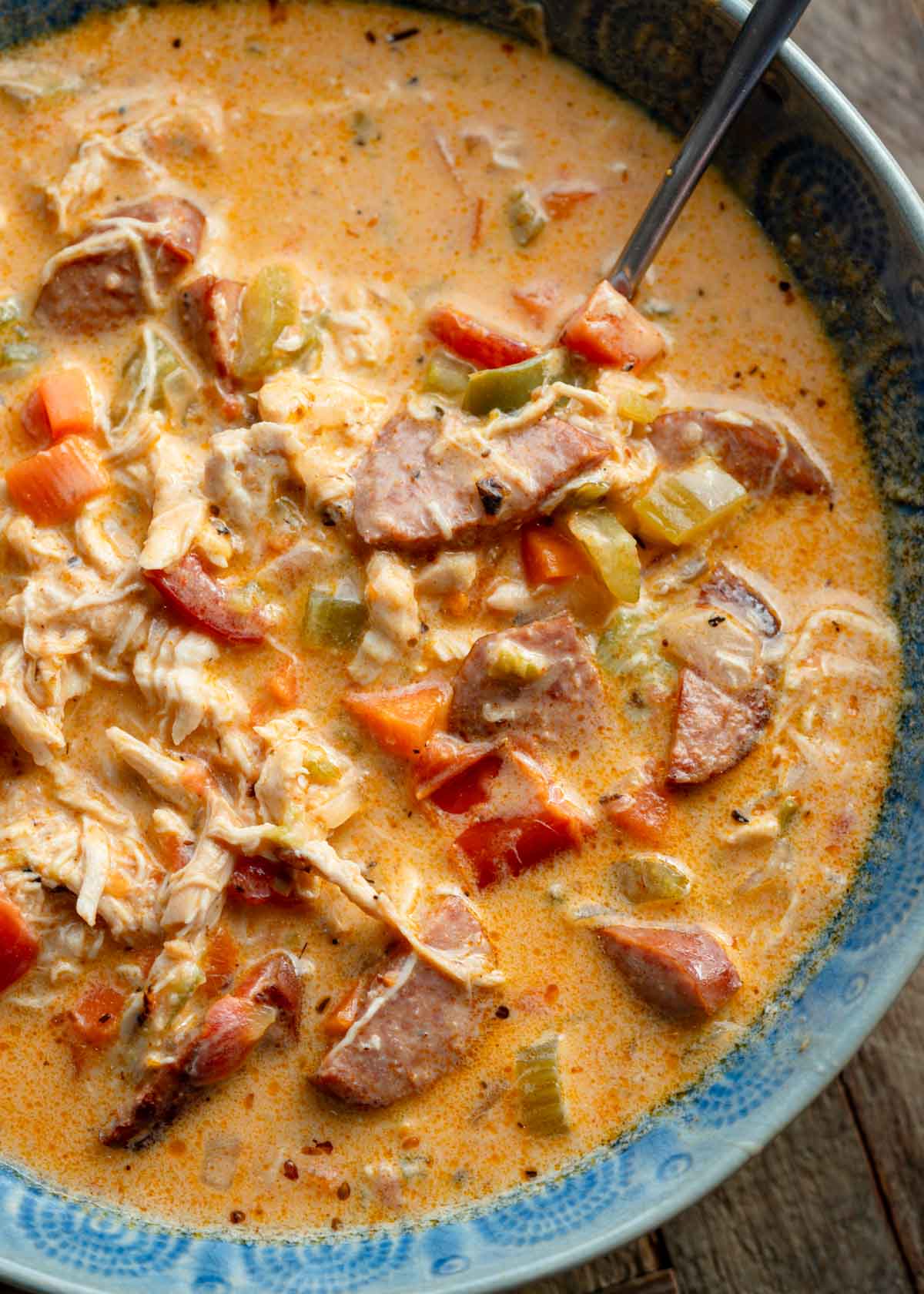 a bowl full of creamy cajun chicken and sausage soup with a spoon