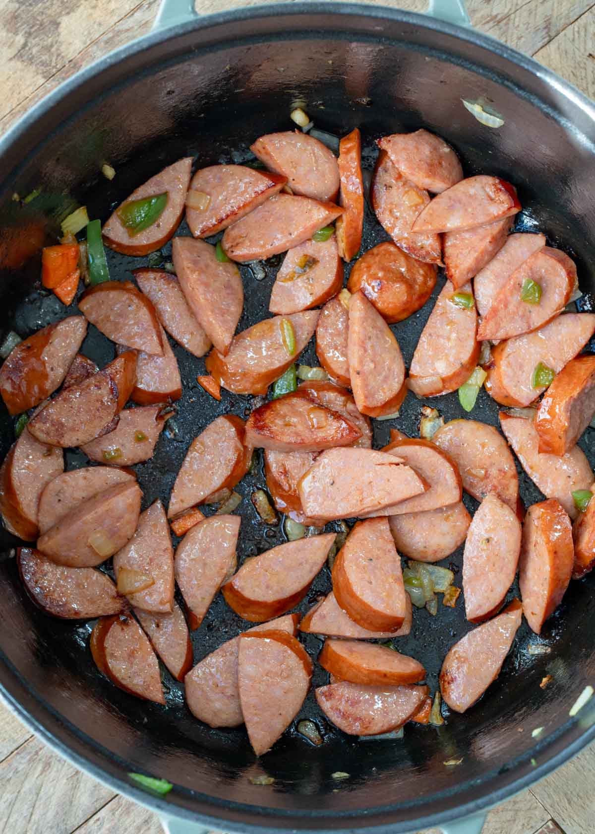 sliced andouille sausage browning in a pot