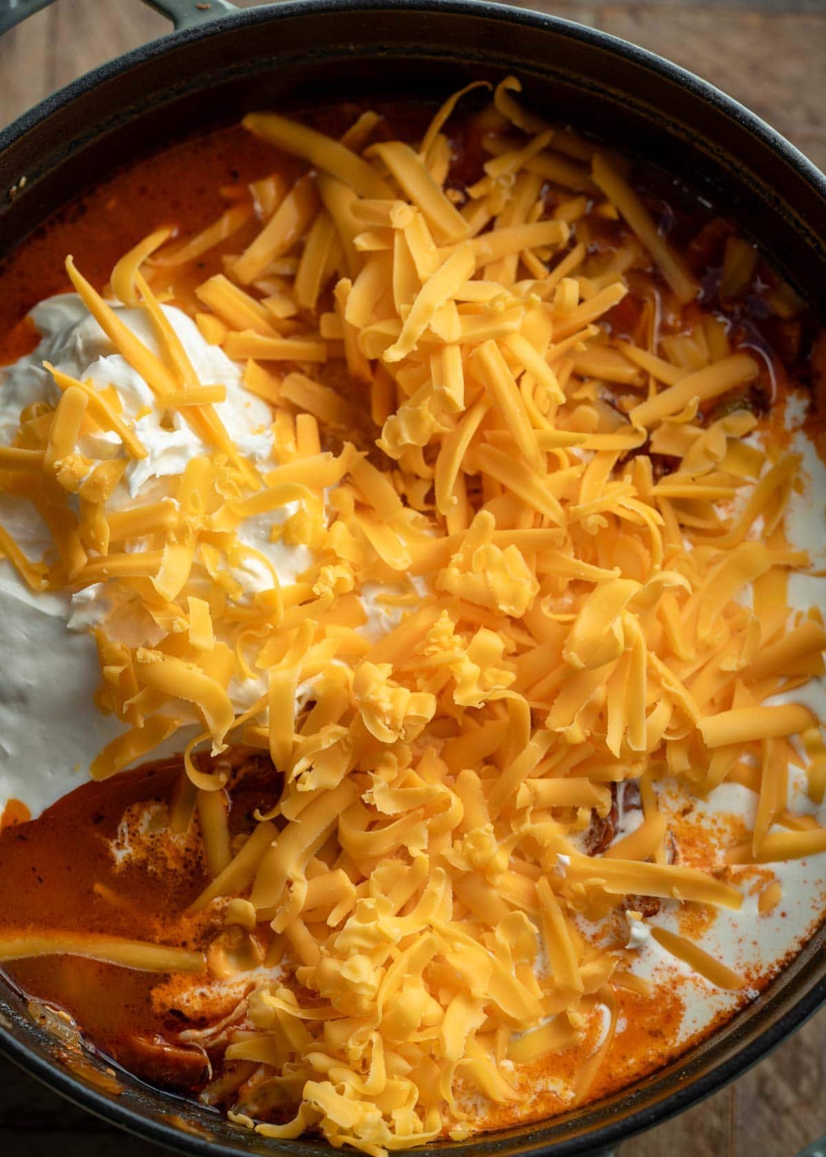 cream cheese, heavy cream, and shredded cheese in a pot of soup