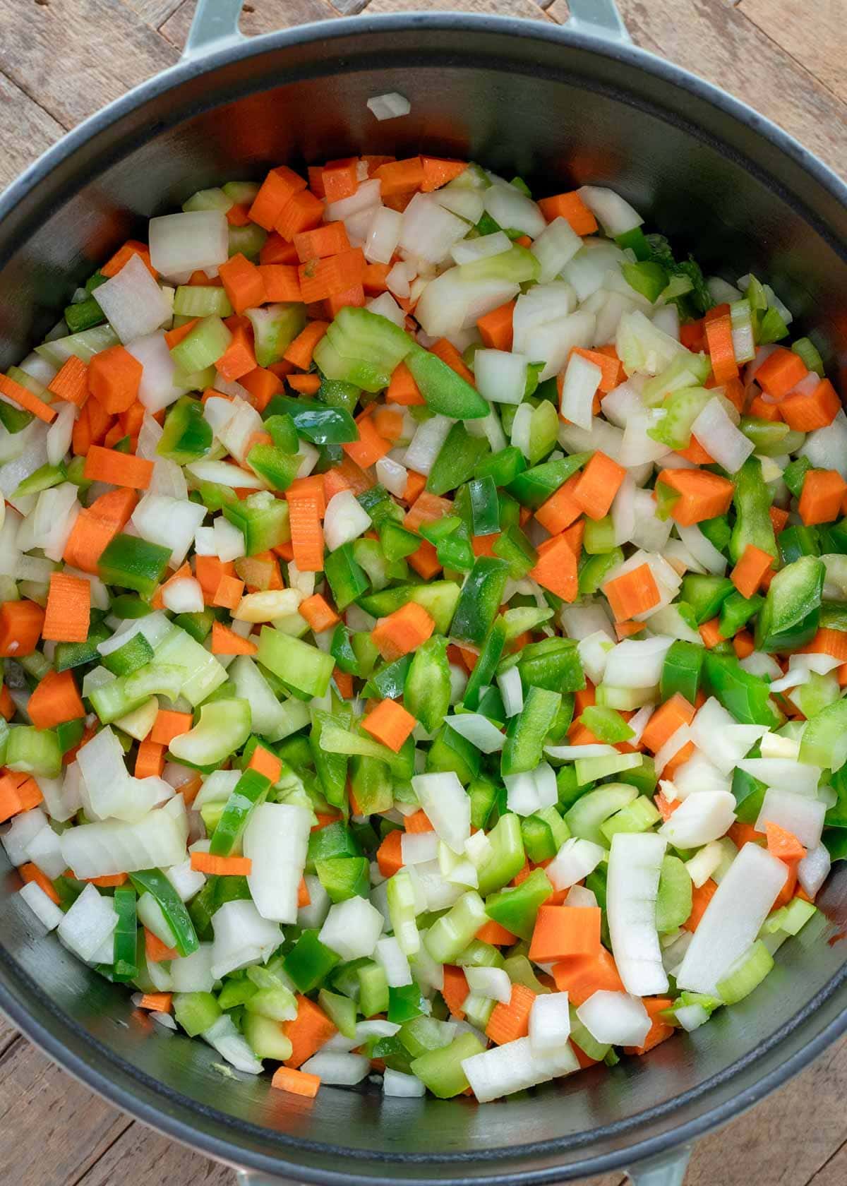 chopped carrots, onions, celery, bell pepper, and garlic sauteing in a dutch oven
