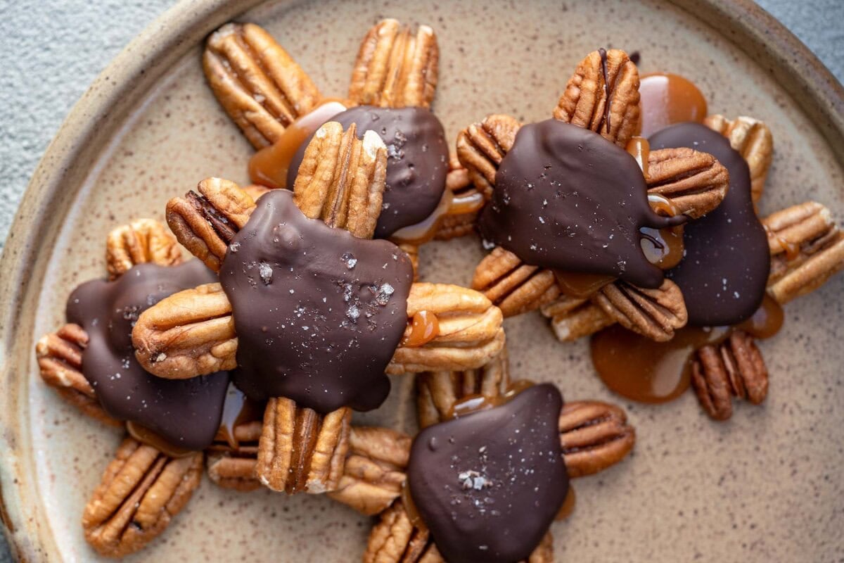 six chocolate pecan turtles on a plate