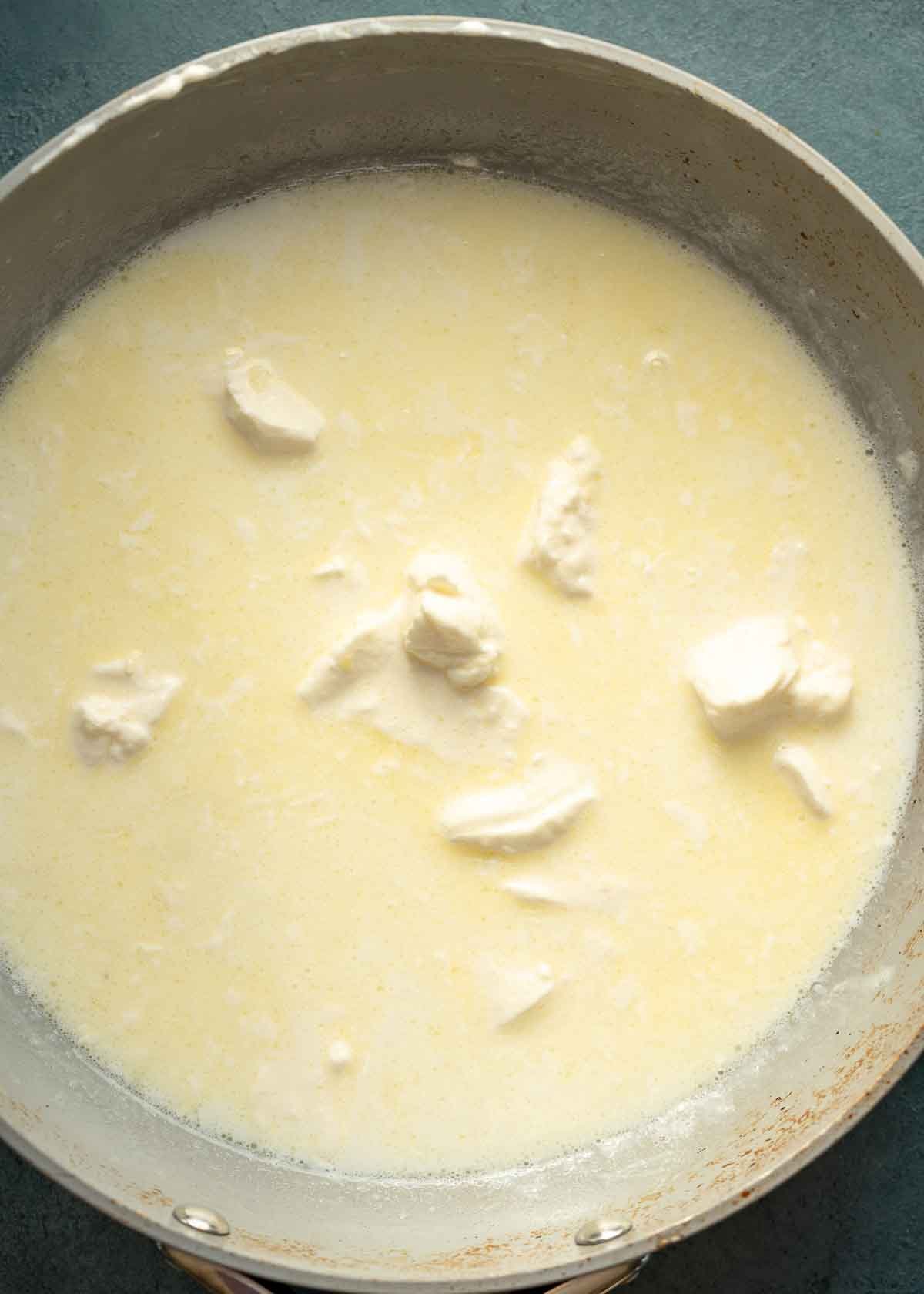 butter, garlic, milk, heavy cream, and cream cheese in a pan